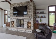 a living room with a large stone fireplace and flat screen tv mounted above the fire place