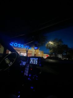 the dashboard of a car at night in front of a building with a neon sign