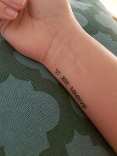 a woman's arm with a small wrist tattoo that reads, v w march