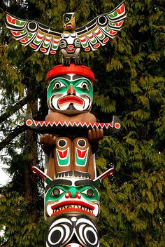 three totems are stacked on top of each other in front of some trees