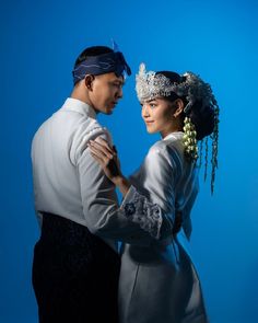 a man and woman dressed in traditional chinese garb dance together against a blue background