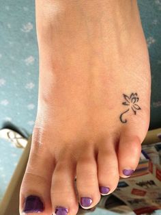 a woman's foot with purple nail polish and flower tattoo on her left toe