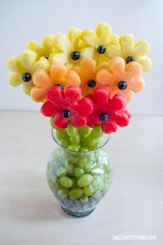 a glass vase filled with watermelon flowers and grapes on top of a table