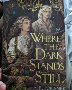 a person holding up a book in front of their face with the title where the dark stands still