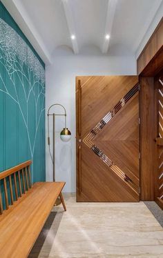 a wooden bench sitting in front of a blue wall next to a door with an abstract design on it