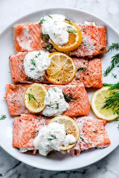 salmon with dill sauce and lemon slices on a white plate