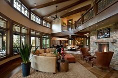 a living room filled with lots of furniture next to a fire place and large windows