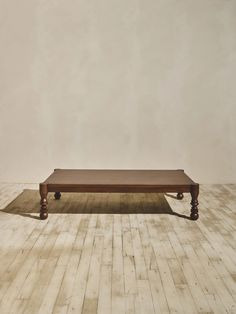 a wooden table sitting on top of a hard wood floor next to a white wall