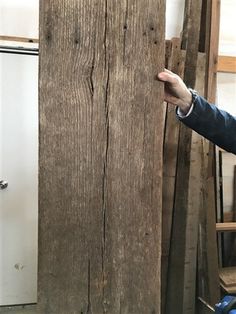 a man is pointing at a piece of wood that has been nailed to the wall