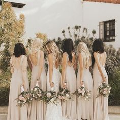 a group of women standing next to each other in long dresses and holding bouquets