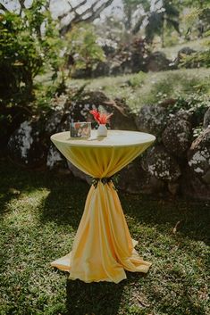 a table with a yellow cloth draped over it in the middle of a grassy area