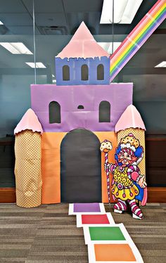 an inflatable castle sits on the floor next to a rainbow colored rug and door