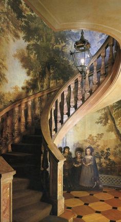 a staircase with paintings on the wall and people standing at the bottom, in front of it