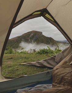 the view from inside a tent looking out at mountains and fog in the distance, with a sleeping bag on the ground