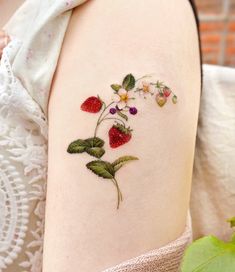 a close up of a person's arm with flowers and strawberries on it