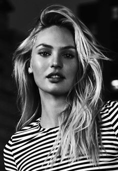 a black and white photo of a woman with long blonde hair wearing a striped shirt