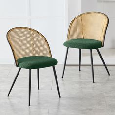 two chairs with green upholstered cushions and black metal legs, side by side