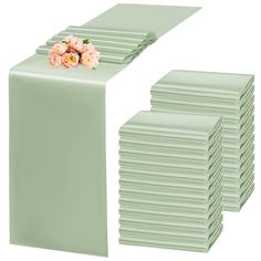 a stack of mint green table runners with pink flowers on each side and white background