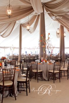 the inside of a tent with tables and chairs set up for a formal function,