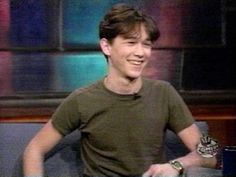 a young man is smiling while standing in front of a television screen with his hands on his hips