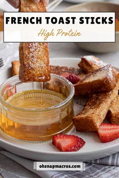 french toast sticks are being dipped with honey and syrup on a plate next to strawberries