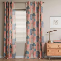 a living room with curtains and a dresser in front of a window that has an abstract design on it