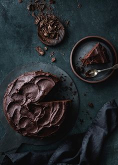 a piece of chocolate cake on a plate next to a fork and bowl with the rest of it