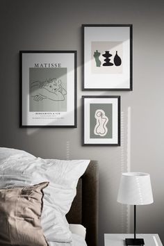 three framed pictures hang on the wall above a bed in a room with white sheets and pillows