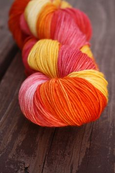 two skeins of yarn sitting on top of a wooden table