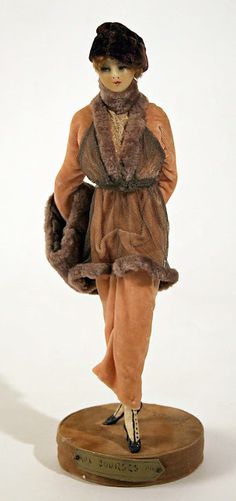 a figurine of a woman in a fur coat and hat on a wooden base