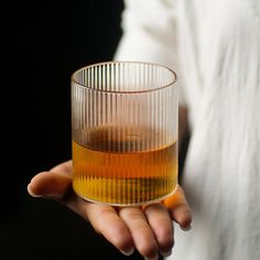 a person holding a glass with liquid in it