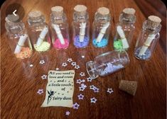 small bottles filled with different colored glitters on top of a wooden table next to a note