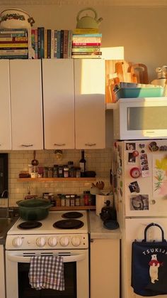 a kitchen with white appliances and lots of clutter on the counter top, along with bookshelves