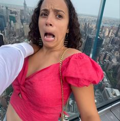 a woman with her mouth open standing on top of a building