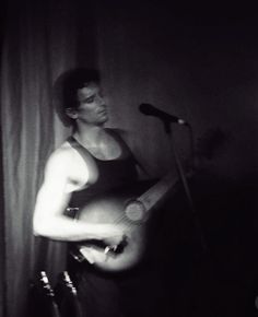 a man holding an acoustic guitar in front of a microphone