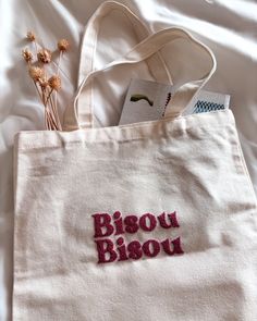 a white bag with the words bisou bibou on it and some flowers