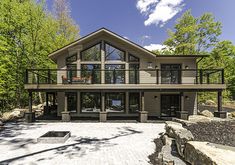 a large house surrounded by trees in the middle of a wooded area with rocks and gravel