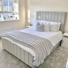 a bed with white sheets and pillows in a bedroom next to a wall mounted radiator