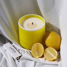 a yellow candle and some lemons on a white sheet