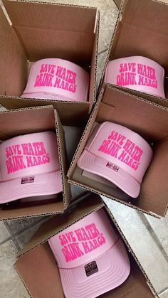 six pink hats are in a box on the floor, with save water drink milk