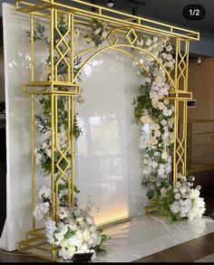 a white and gold wedding arch decorated with flowers