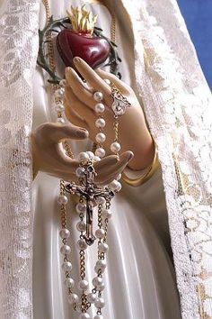 an image of a statue with pearls and beads on it's arm holding a heart