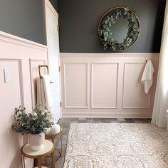 a bathroom decorated in pink and gray with a wreath on the wall