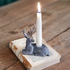 a candle sitting on top of an old book with a deer figurine next to it