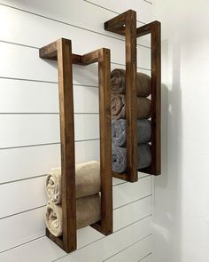 two wooden shelves holding towels and folded towels in a bathroom with white shiping walls