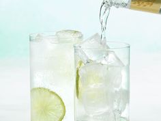 two glasses filled with ice and limes next to each other