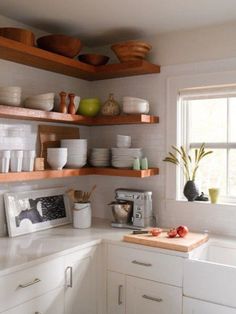 a kitchen with white cabinets and shelves filled with dishes on top of wooden counter tops