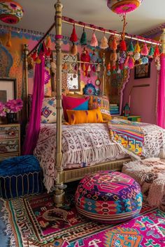 a colorful bedroom with lots of pillows and rugs on the floor, including a canopy bed