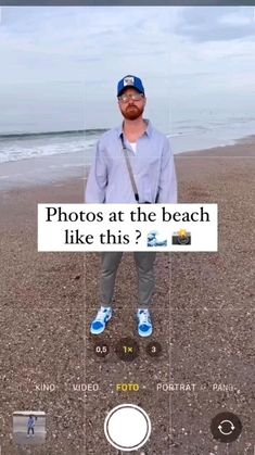 a man standing on top of a sandy beach next to the ocean holding a camera