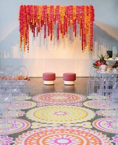 chairs are set up in front of a colorful carpet with flowers hanging from the ceiling